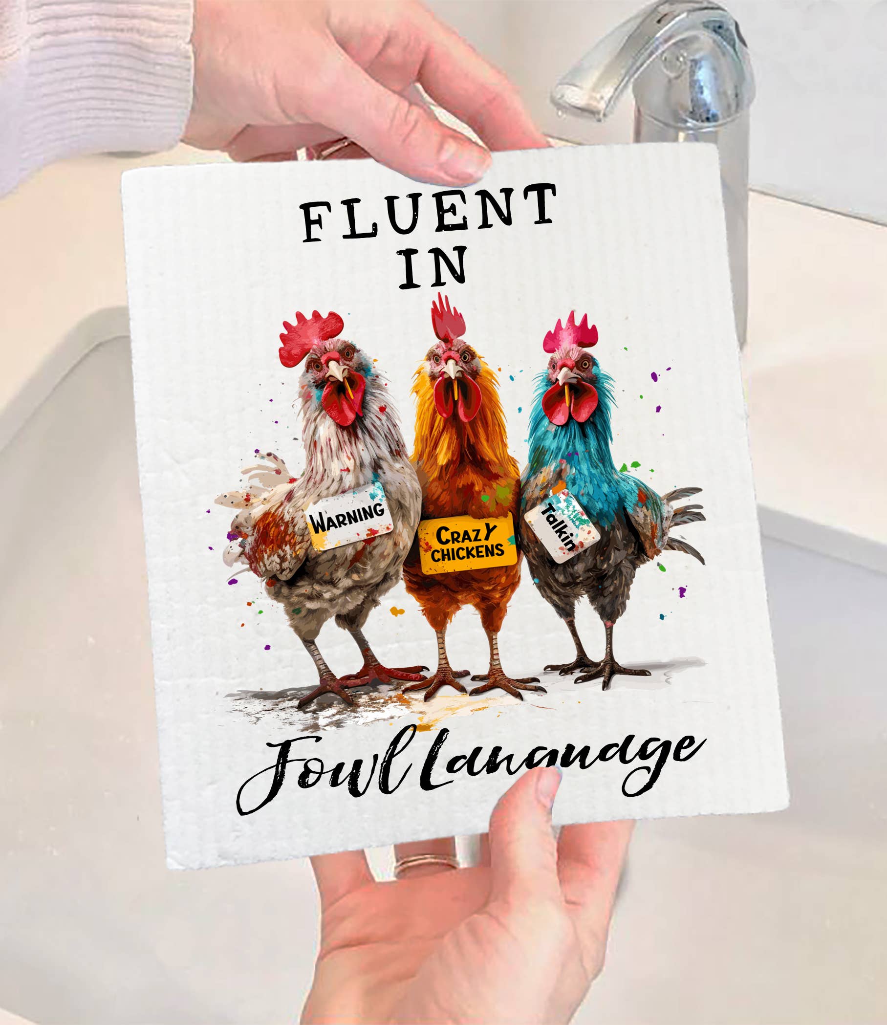 Someone holds the Dish Cloth: Fluent in Fowl Language Funny Saying SWEDISH DISH CLOTH, featuring three illustrated chickens with signs—Warning, Crazy Chickens, Fowl Mouth—and the phrase Fluent in Fowl Language. Eco-friendly and humorous!.