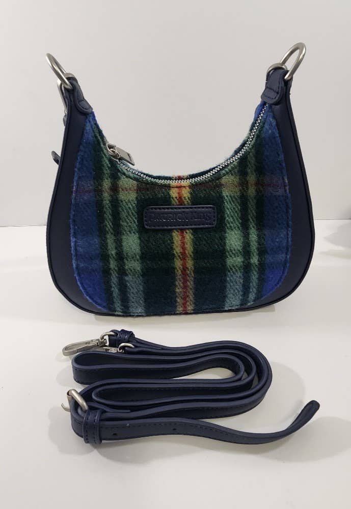 The Tartan Merino Wool Bag - Nova Scotia is a small shoulder bag with a green, blue, and red plaid wool front inspired by the Nova Scotia tartan, navy leather sides, and a matching detachable strap placed in front.