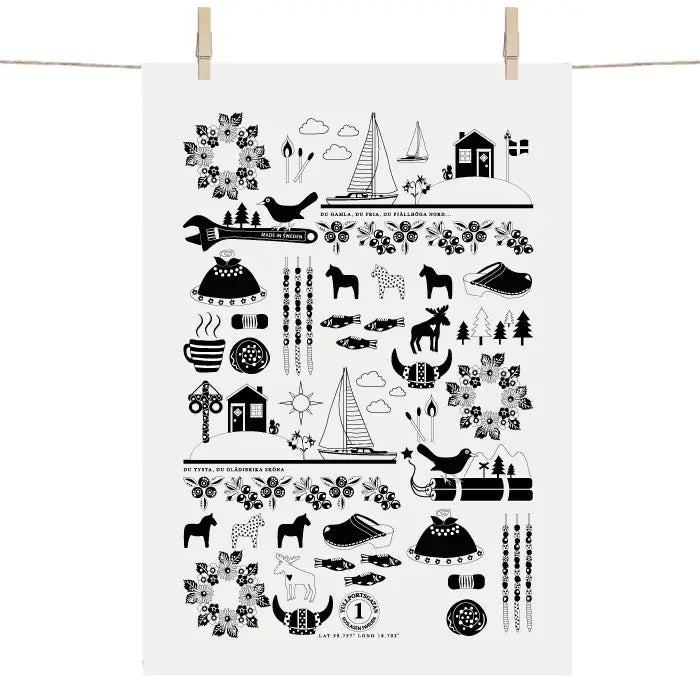 Scandinavian-style black and white tea towel by Anneko Design Sweden features horses, birds, flowers, cabins, sailboats, skis, and trees in a symmetrical pattern. Product: Made in Sweden Tea Towel.