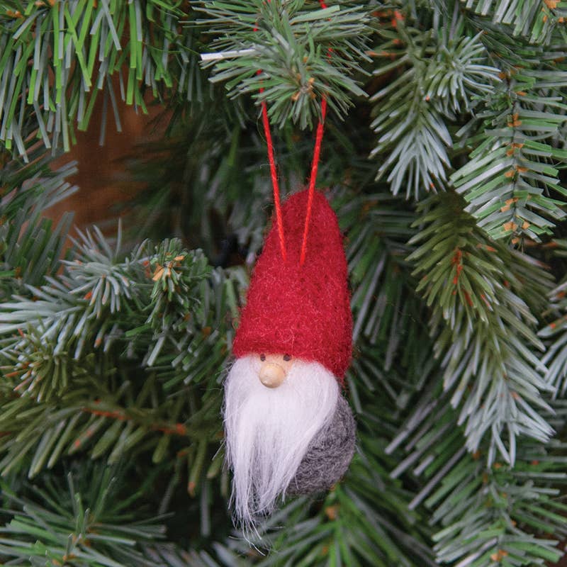 The Ornament: Felted Mini Red Hat Tomte - Nisse - Gnome 3, featuring a white beard, hangs on a green Christmas tree branch.