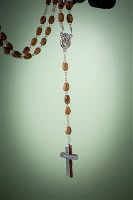 The Olive Wood Rosary with Crucifix from the Holy Land, made in Bethlehem, Israel, featuring oval beads and a metal crucifix, is displayed against a plain light green background.