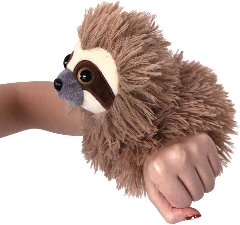 A person’s hand holds the Plush: Sloth Slap Bracelet Slapstix, featuring a furry 7 sloth body and large eyes, with the bracelet extending to 10 long, resembling a cuddly plush toy.