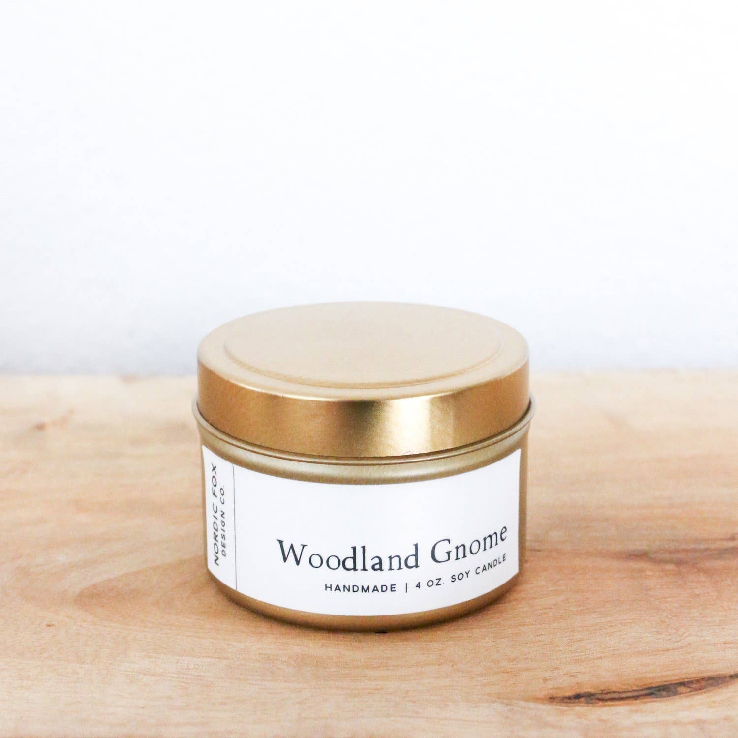 An 8 oz. Woodland Gnome Handmade Soy Candle in a glass jar sits on a wooden surface against a plain white background, making it the perfect festive candle for the Christmas holiday season.
