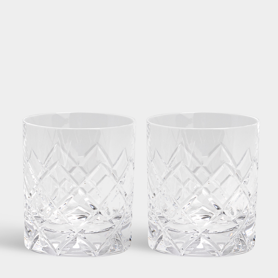 Two clear, patterned glasses sit elegantly on a plain grey background, part of the Orrefors: Sofiero Double Old Fashioned (2-Pack), masterfully crafted by renowned designer Gunnar Cyrén.
