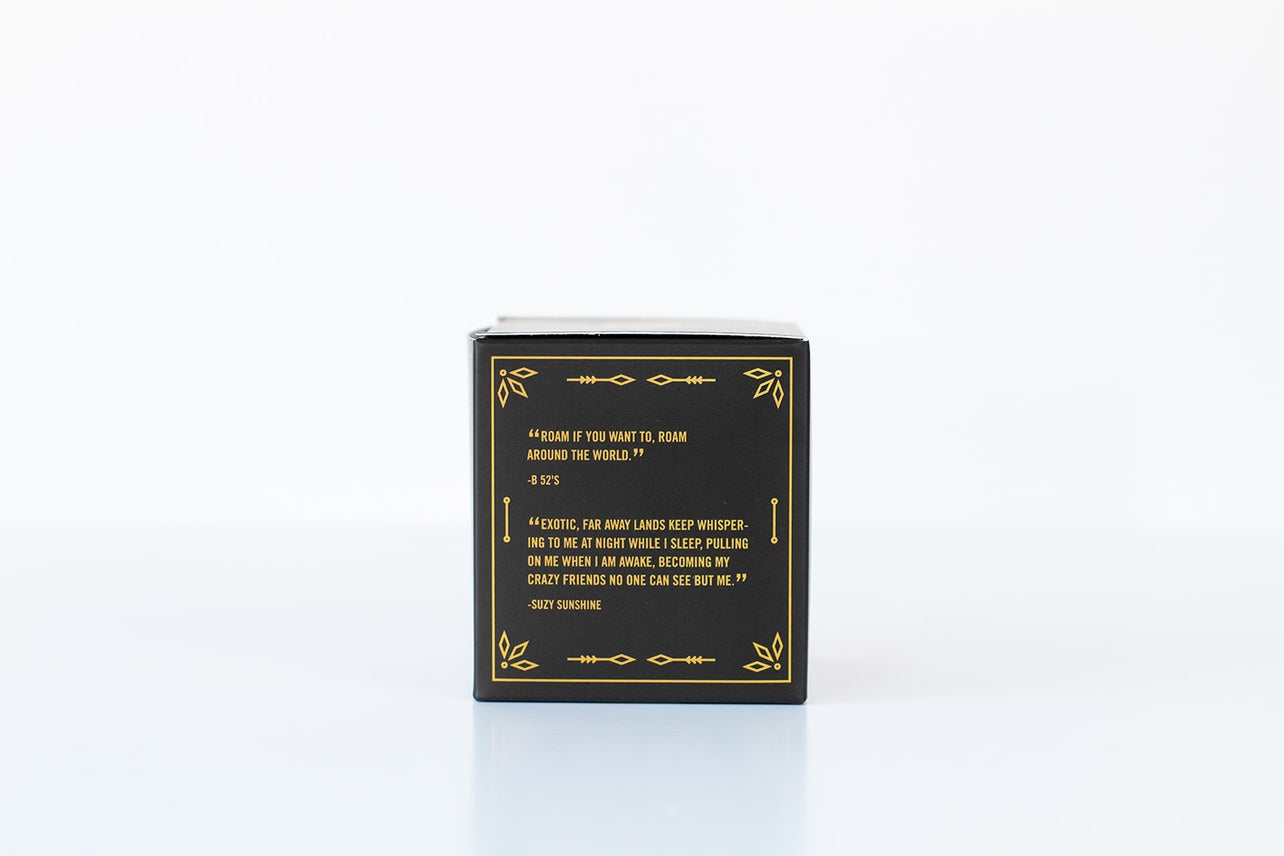 A black box with gold accents shows a yellow quote on one side; inside is the Bath Bomb: Sandalwood & Vanilla, made with nourishing ingredients, all set against a plain white background.