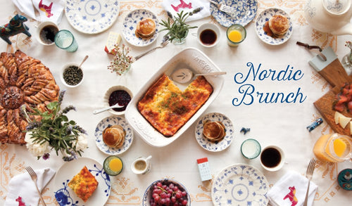 A table set for brunch with pastries, fruit, and drinks evokes cozy Nordic vibes inspired by "Book: Scandinavian Gatherings" (paperback) by Melissa Bahen from Penguin Random House, with the book title displayed on the right side.