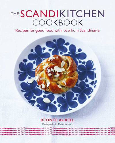Cover of Book: ScandiKitchen Cookbook by Bronte Aurell, showing a pastry topped with almond slices on a blue-patterned plate atop a white cloth with red stitching—a great introduction to Scandinavian cuisine.