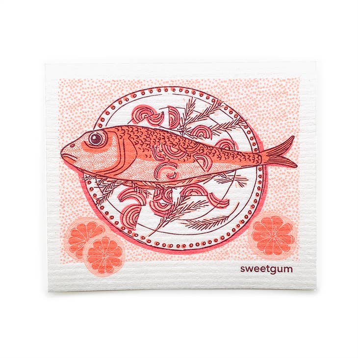 The Dish Cloth: Fish Dinner on a Plate features a fish illustration on a patterned plate with citrus slices, in red and pink hues, plus "sweetgum" printed in the corner—a decorative Swedish-inspired napkin.