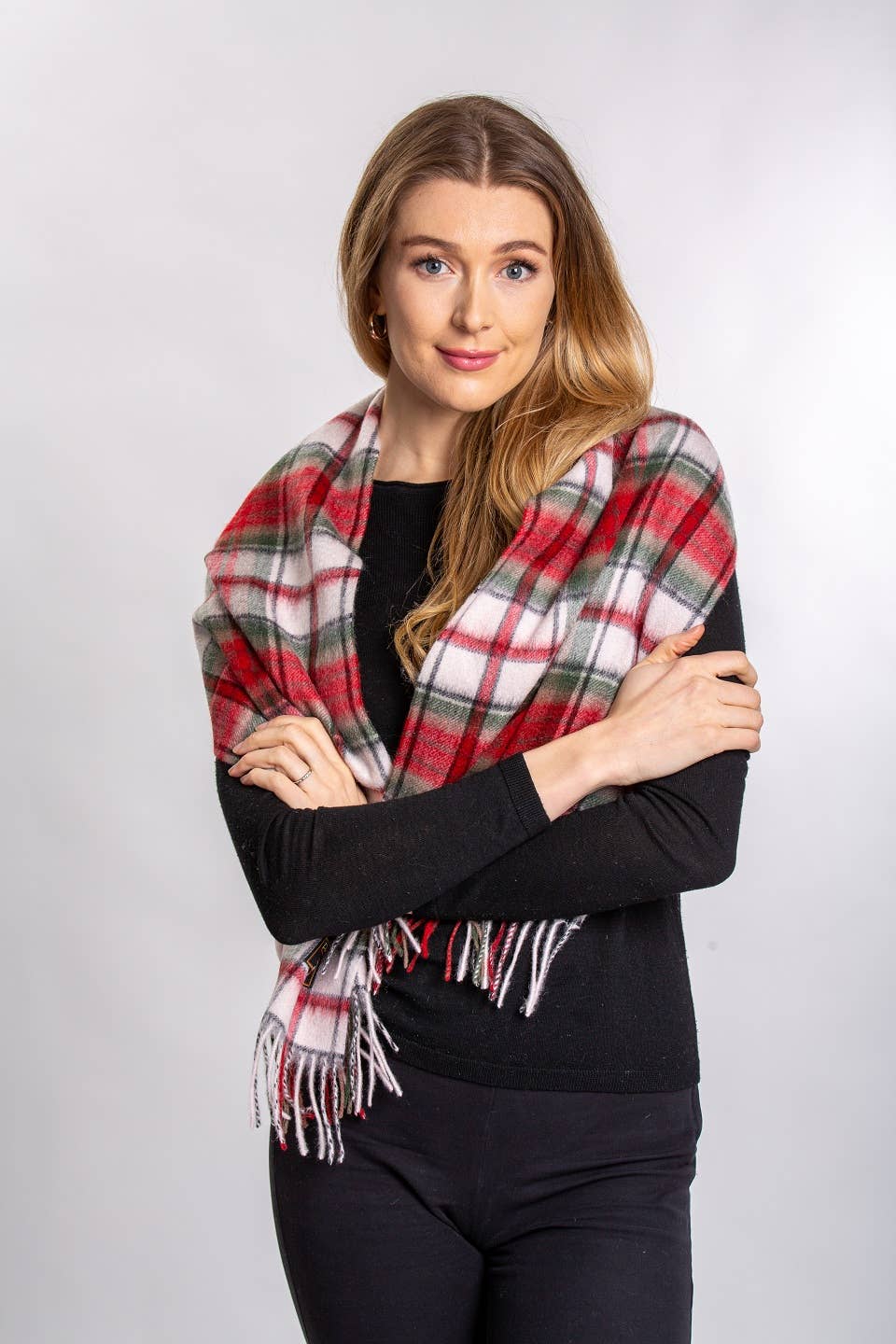 Woman with long hair, wearing a black top and the MacDuff Lambswool Scarf, stands with arms crossed in front of a plain light background.
