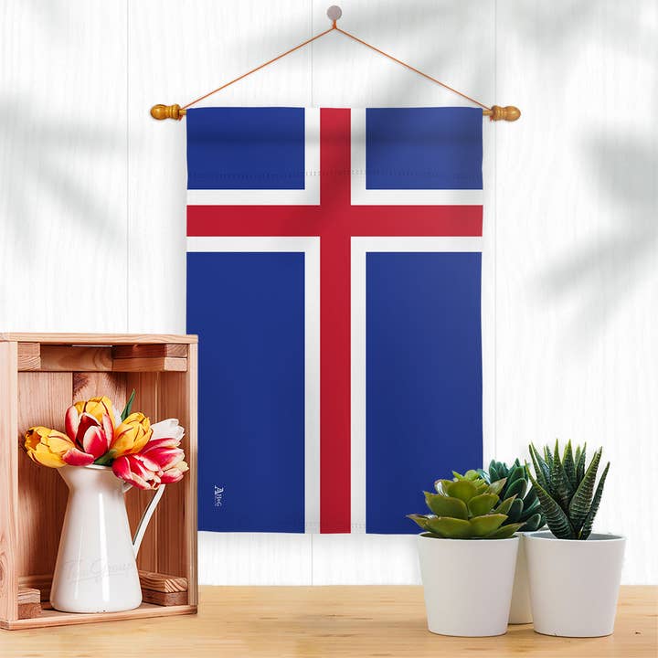 The Flag: Iceland Garden Flag - Icelandic Nationality Decor Flag, made from weather-resistant fabric, hangs above a table with a wooden crate, vase of flowers, and succulents—celebrating Icelandic heritage in style.