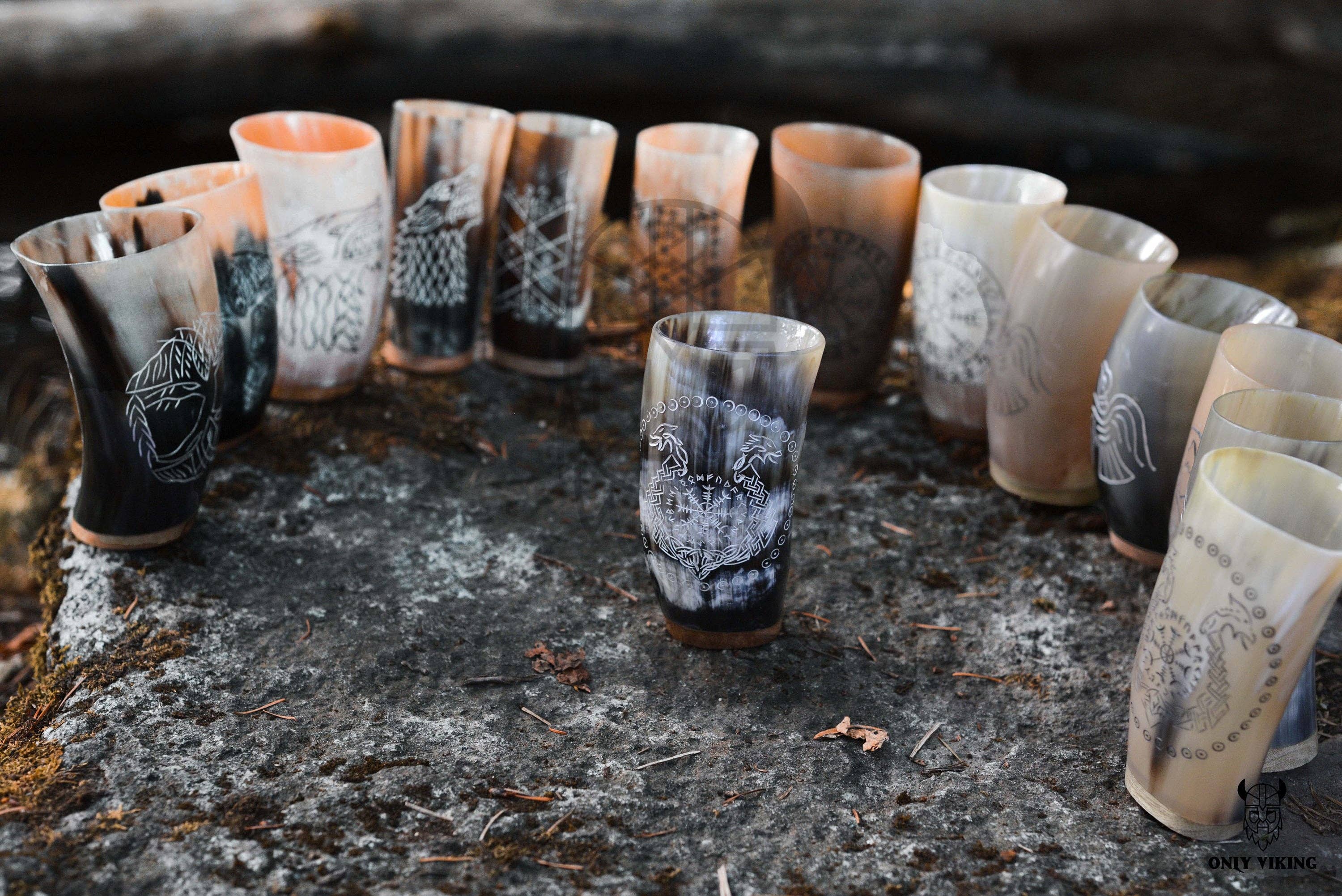 The Horn Mug: Beer Stein Drinking Horn Mug Tree of Life (6-9 oz) features Norse-inspired engraving and sits outdoors on a large, flat rock.