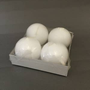 A small cardboard tray holds four 2.5" diameter white ball candles, each neatly wrapped in clear plastic.