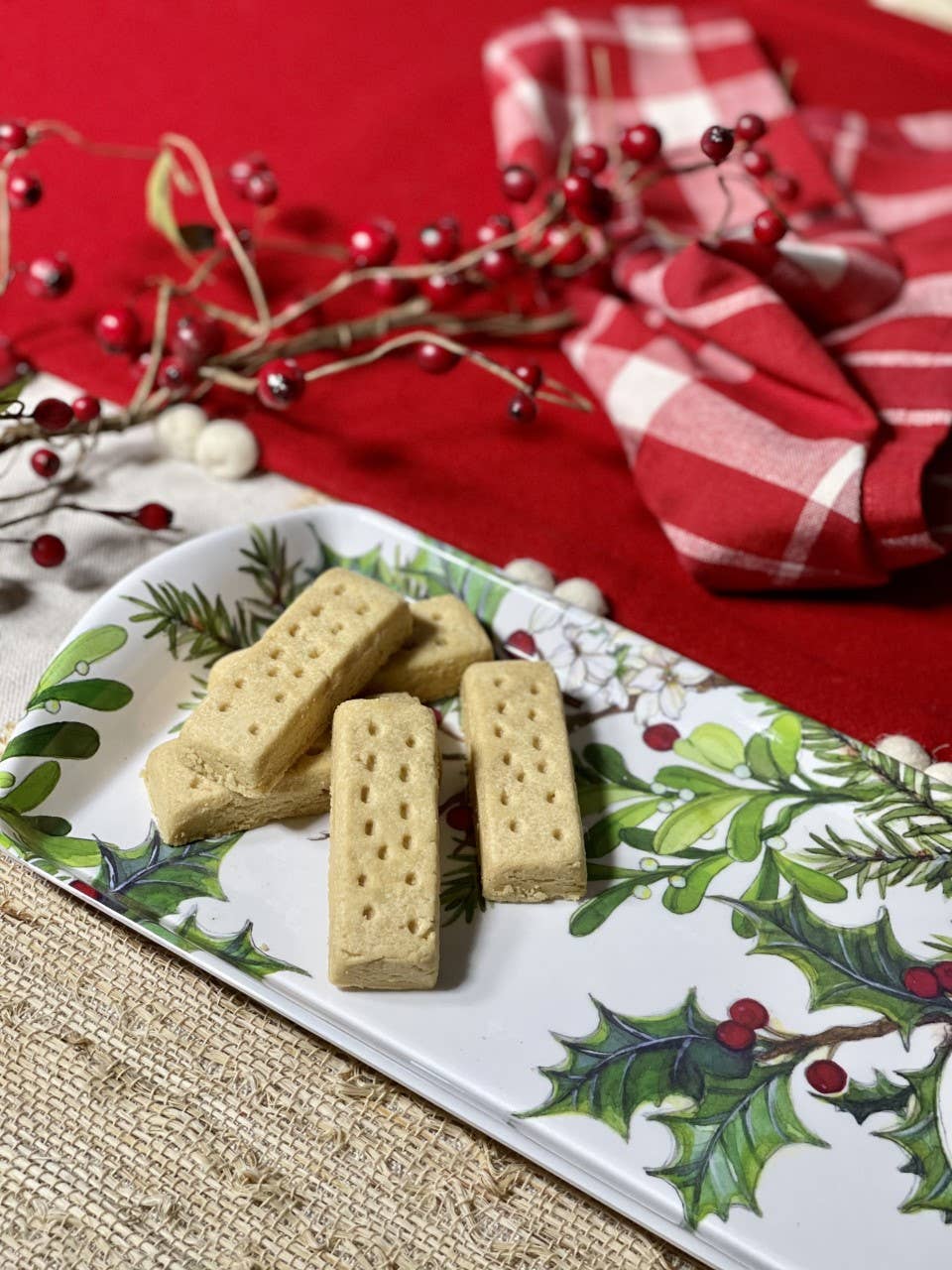 Rectangular shortbread cookies on the Holly & Berries Holiday Serving Appetizer, Almond Cake, Bread Loaf Tray with red berries and a red plaid napkin on a festive table setting.