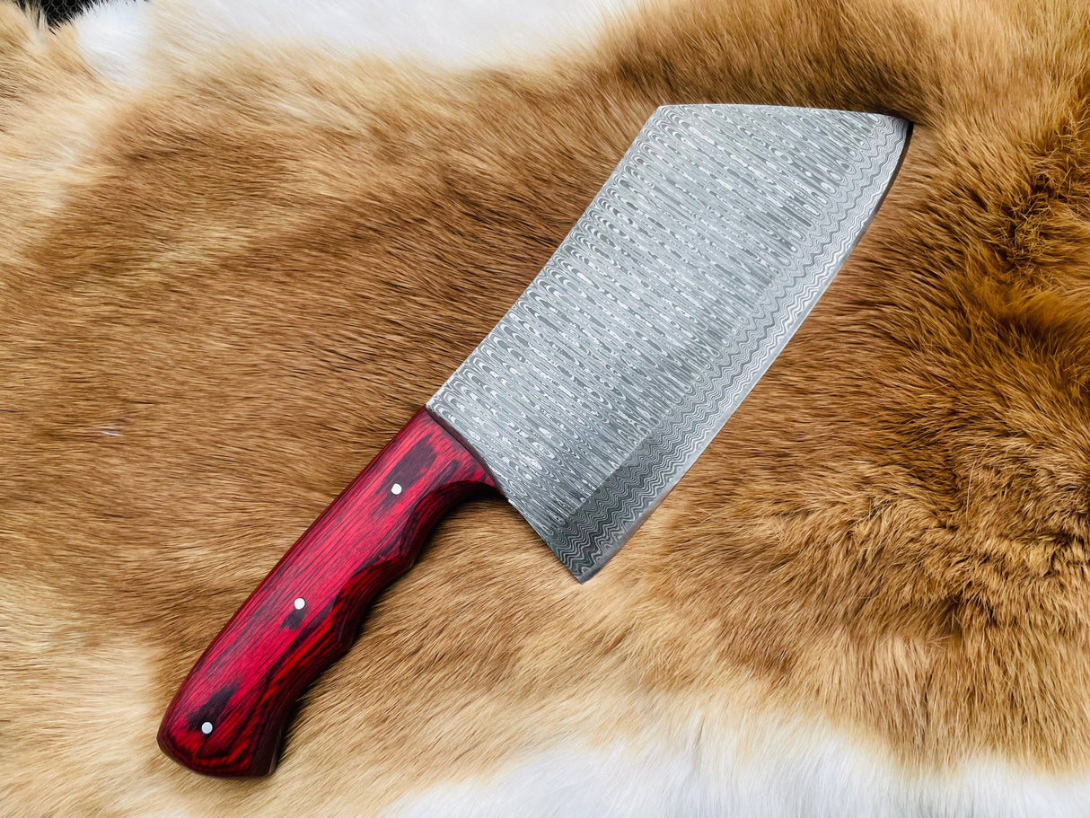 The Knife: Custom Damascus Steel Cleaver Red Handle Chinese Cleaver is a large cleaver with a bold red handle, displayed on a brown and white fur surface.
