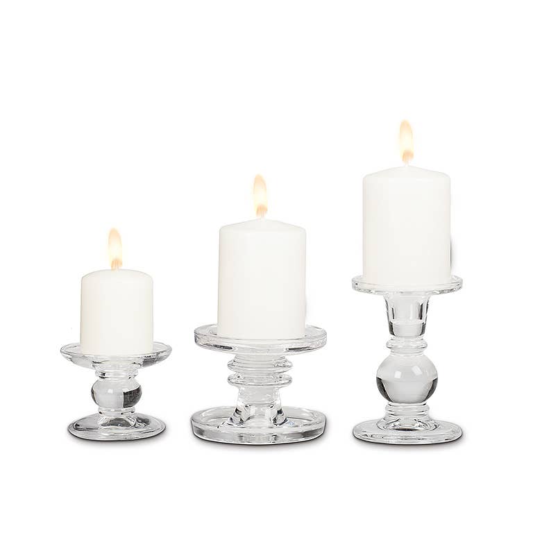 A white pillar candle burns atop the Small Reversible Candle Holder-3.5"L, adding a sophisticated touch to any setting.