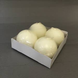 Four Ivory Ball Candles, 2.5" diameter, are arranged in a white cardboard tray against a plain gray background.