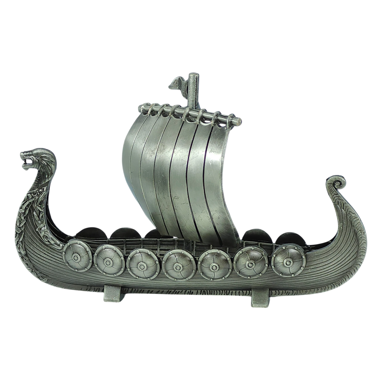 Celebrate Scandinavian heritage with the Figurine: Norwegian Viking Ship with Sail Pewter 5″x3″ Table Decor by Faire - Scandinavian Specialties. Expertly handcrafted, this metallic model features a striking dragon head at the prow, detailed round shields along the sides, and a classic sail—beautifully presented against a plain white background and capturing the spirit of Norway’s iconic longships.