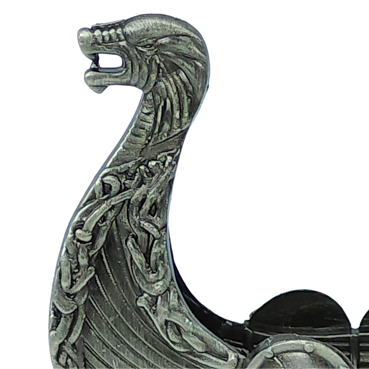 A close-up of the “Norwegian Viking Ship with Sail Pewter 5′‘x3’’ Table Decor” by Faire - Scandinavian Specialties, showcasing the figurine’s intricately detailed metallic dragon head prow adorned with knotwork patterns inspired by traditional Norwegian craftsmanship.