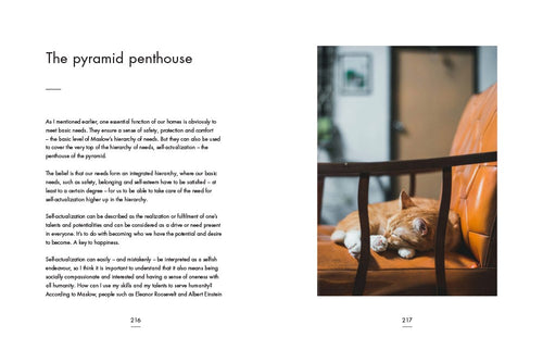 A cozy, orange cat naps on a wooden chair, embodying the essence of Danish design and Hygge, next to an open book titled "My Hygge Home.