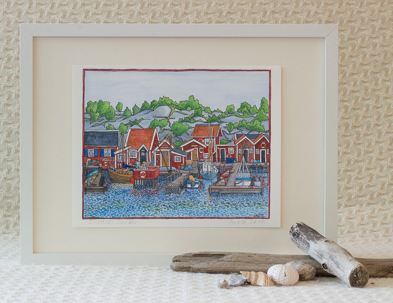 The Artwork: "Swedish Harbor" by Greta Lann is a framed art print that captures a vibrant harbor scene in Göteborg, Sweden, showcasing red buildings and boats. The piece is elegantly presented on a textured wall with driftwood and seashells adorning the foreground, creating an enchanting coastal ambiance.