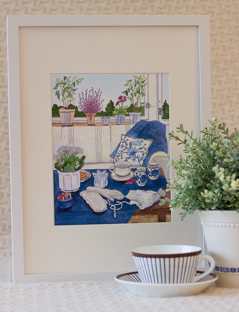 The framed painting January FIKA by Swedish artist Greta Lann portrays a cozy indoor scene featuring plants, a teacup, yarn, and knitting items. The foreground invites you with a realistic potted plant and teacup to experience an authentic Swedish Fika in your own Stockholm-inspired haven.