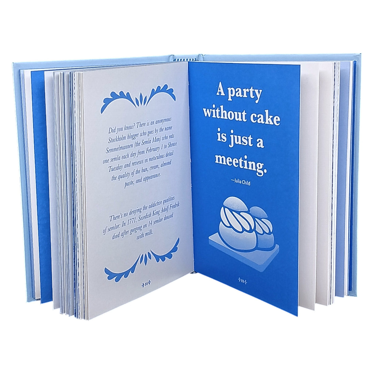 An open copy of "Little Book of Fika" by Lynda Balslev shows a blue page with Julia Child’s quote, “A party without cake is just a meeting,” and cake illustrations—inspiring the Swedish coffee break tradition. The other page has text and decorative borders.