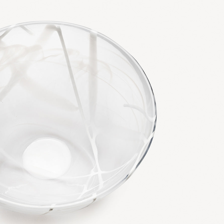 A KostaBoda Contrast Bowl by Anna Ehrner, crafted from clear glass with white, blue, and black veining, displayed on a plain white background.