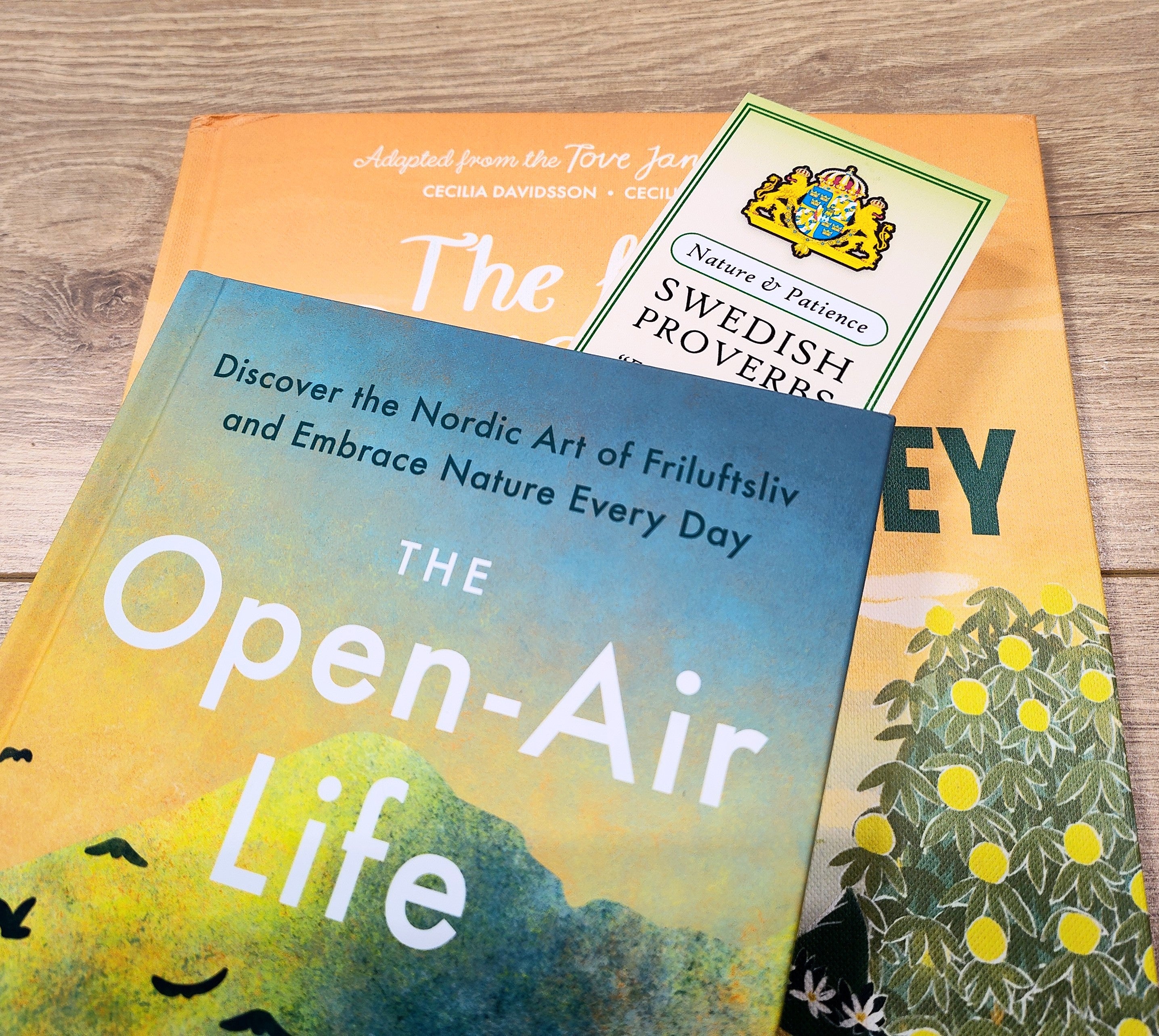 The book The Open-Air Life rests atop another, accompanied by a Bookmark: Swedish Proverbs “Nature & Patience” (2.5" × 8.5"), its label partially visible on a wooden surface and capturing the essence of Scandinavian wisdom.