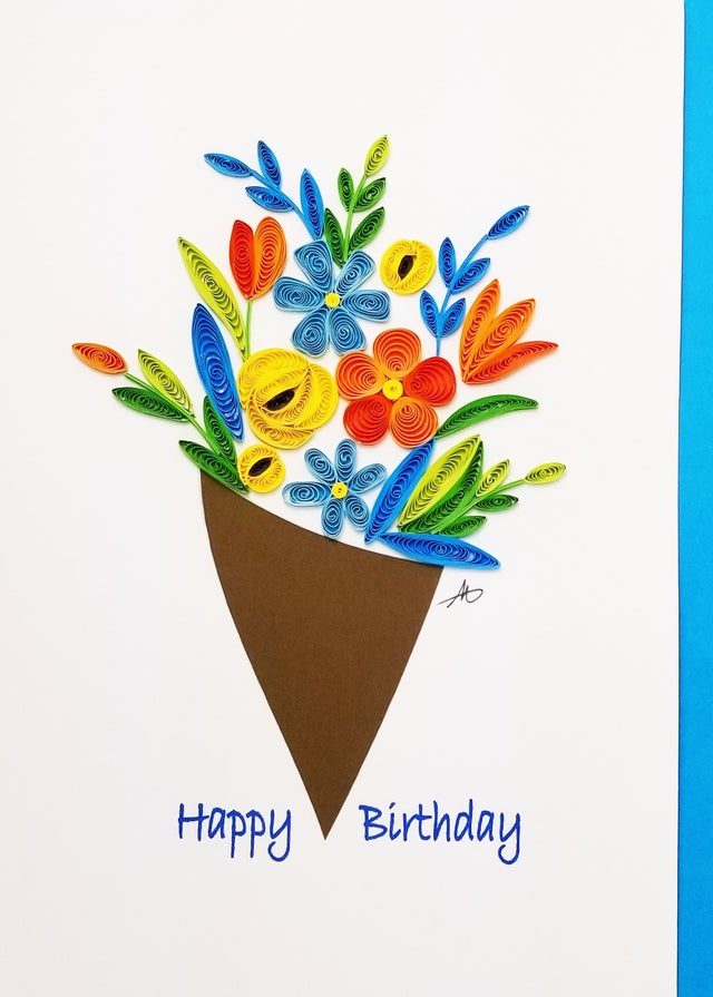 The Cards: Flower Boquet Happy Birthday Quilling Card 5x7 is a handmade birthday card featuring a quilled flower bouquet in a brown cone and Happy Birthday in blue—an ideal choice for a unique gift.