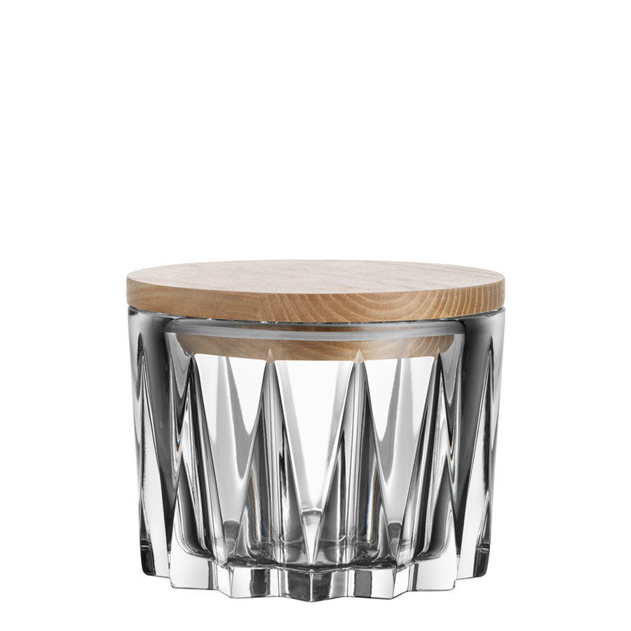 The Orrefors: Sarek Bowl with Lid is a clear glass container featuring a geometric pattern and complemented by a flat wooden lid, inspired by Swedish nature.