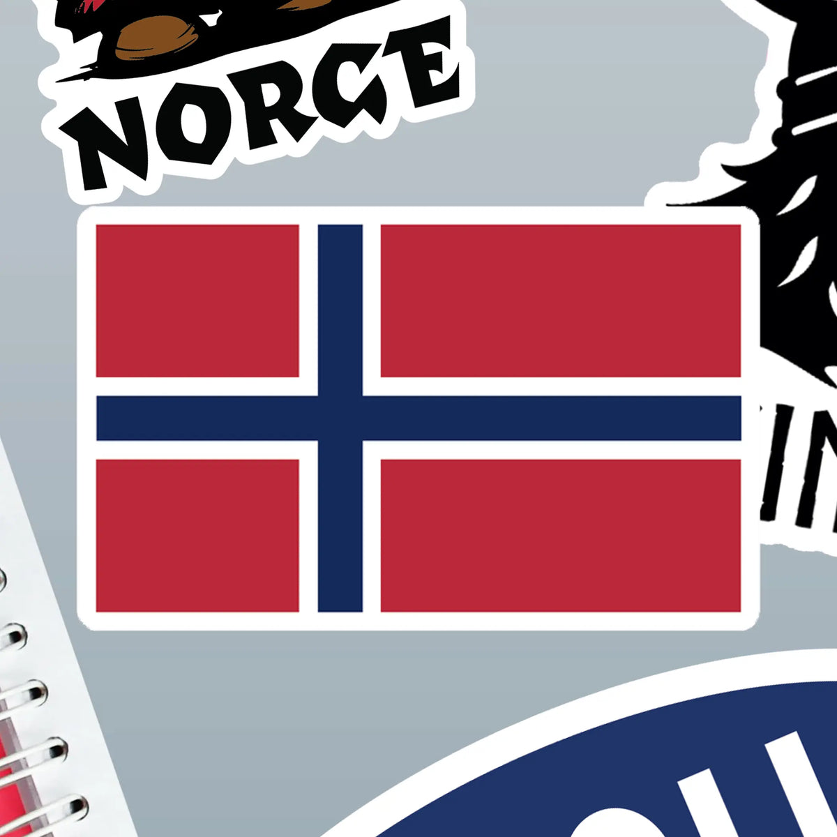 Norwegian flag sticker on a gray surface, next to other Nordic stickers including one with “Norge” text and a bear illustration.