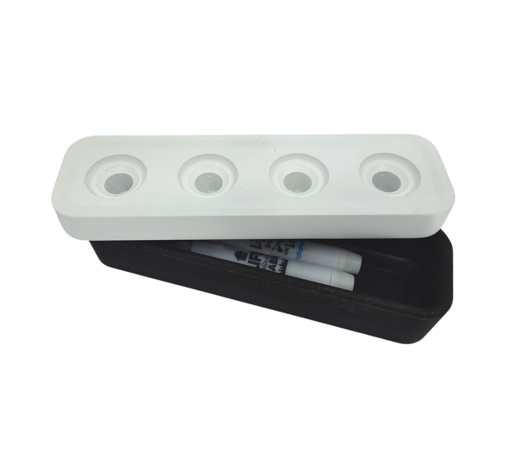 A white plastic Stumpastaken Swedish Candle Holder with four circular slots rests on a sleek black rectangular tray, showcasing two partially visible white tubes. This exemplifies minimalist design and emphasizes environmentally friendly products inspired by Swedish craftsmanship.