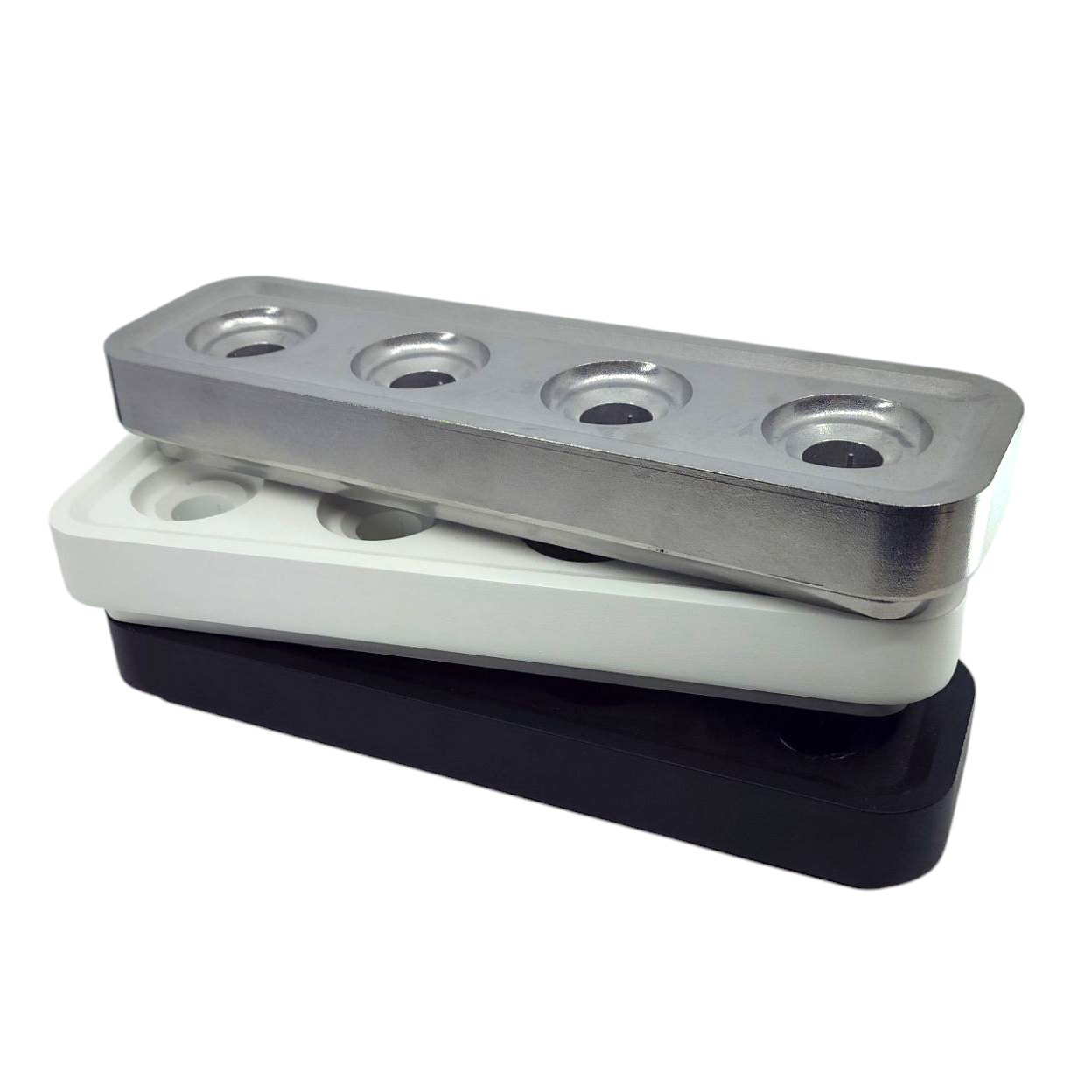 The Stumpastaken Swedish Candle Holder features three sleek rectangular blocks, each with four circular holes, in silver, white, and black. These pieces offer modern elegance and are part of our eco-friendly collection, reflecting our commitment to sustainability.