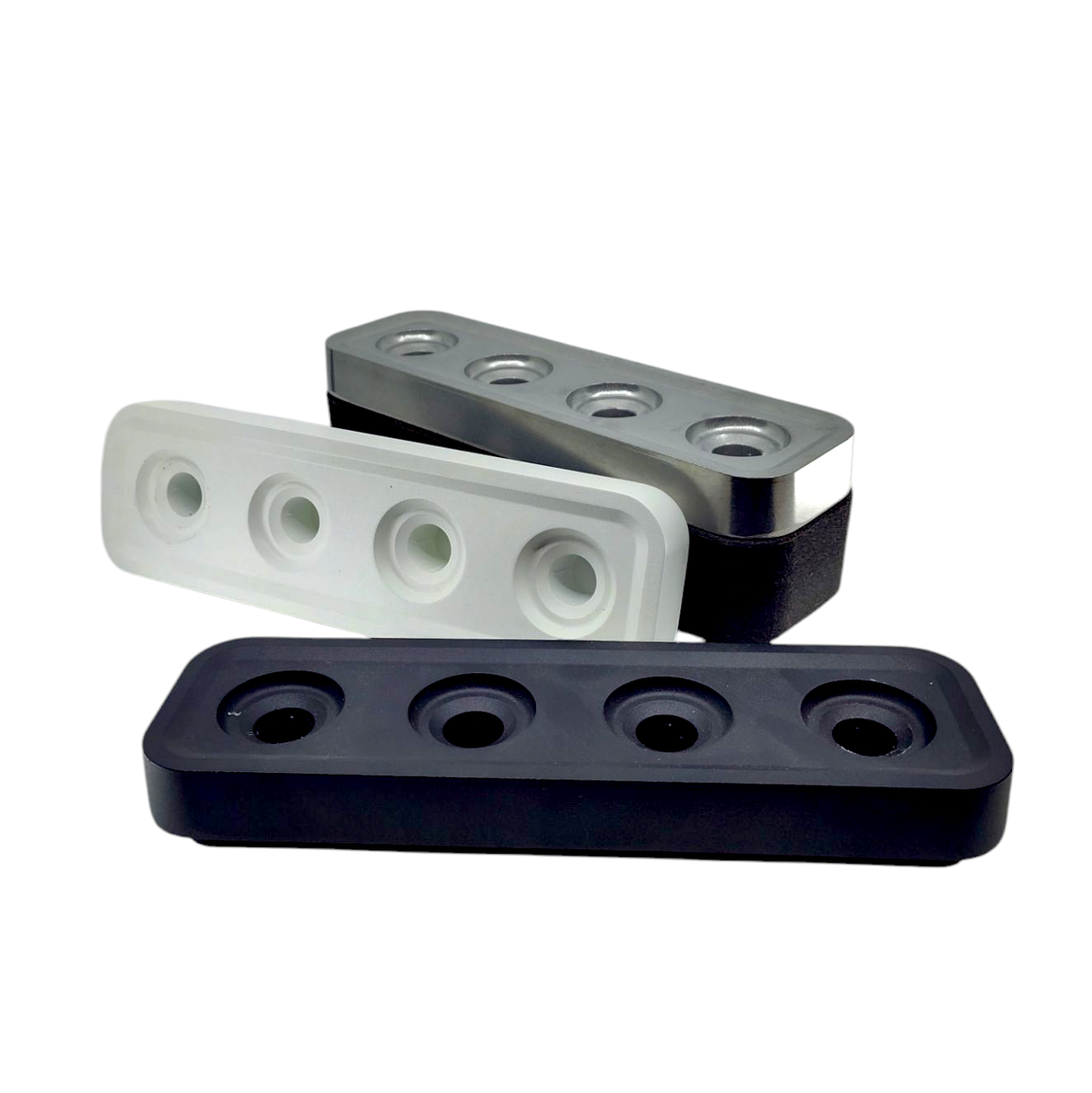 The Stumpastaken Swedish Candle Holder, shown in black, white, and gray with four circular holes each, is stacked at angles against a white background—an eco-friendly way to hold 4 candles.