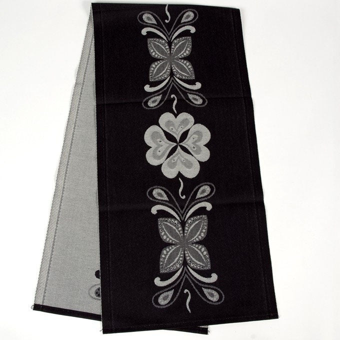 The "Relief" runner by Ekelund Master Weavers of Sweden is crafted from 100% woven cotton and features black, gray, and white symmetrical floral patterns inspired by Swedish kurbits arranged down the center.