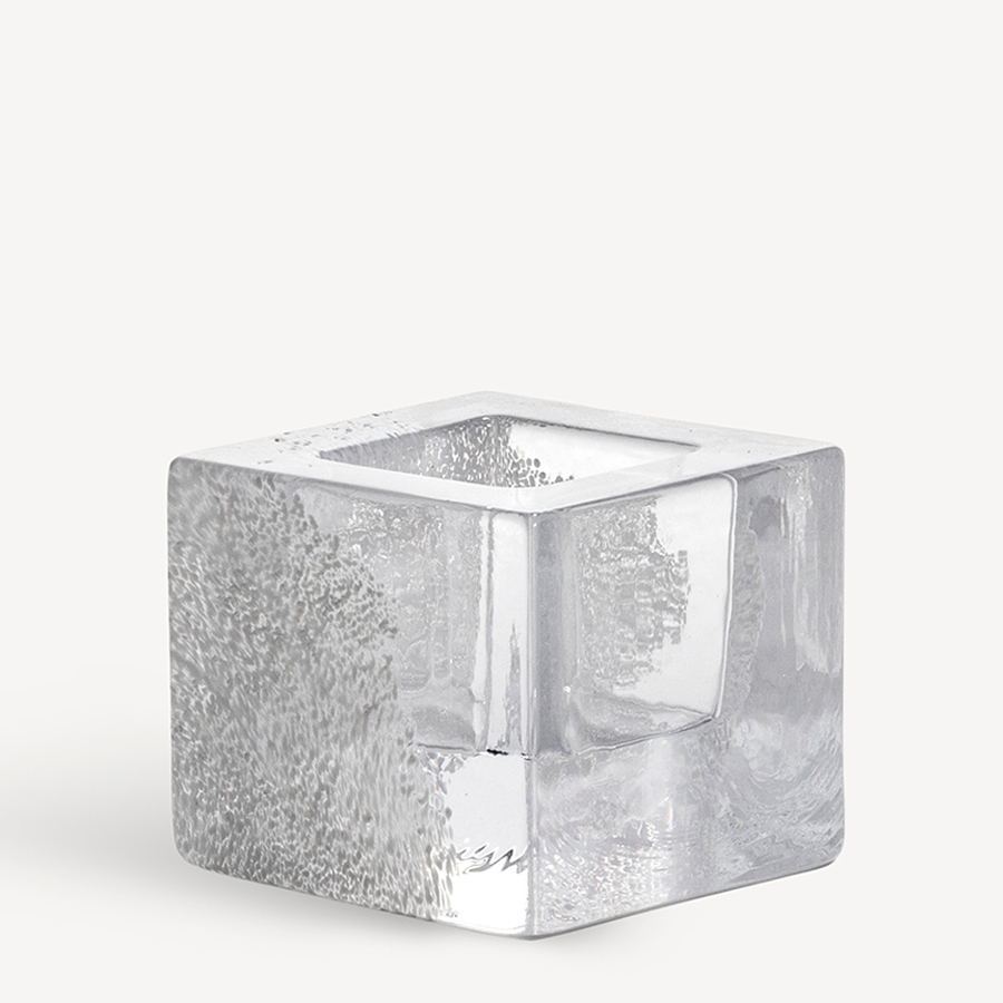 The KostaBoda: Brick Votive Candle Holder, available in 3 colors, features a clear glass cube with a hollow center and textured bubbles inside, elegantly displayed on a plain white background.