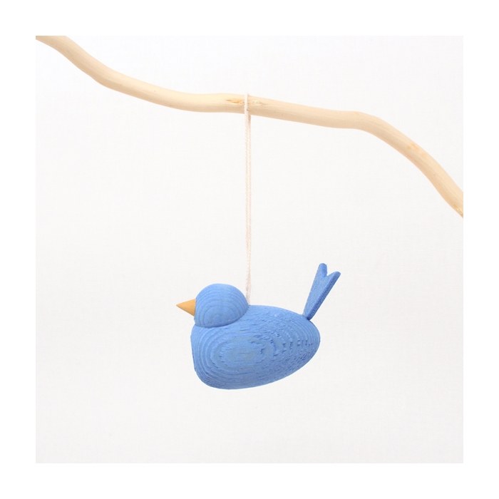 The Ornament: Wooden Scandi Light Bird Blue Hangs on the Tree features a blue wooden bird with a yellow beak, suspended by a string from a branch, creating charming Scandinavian Christmas décor against a white background.