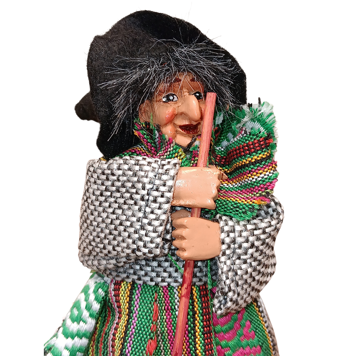The Yasmina Green Kitchen Witch Doll figurine (7" tall) stands on a base, handmade in Germany, wearing a black hat, gray patterned coat, colorful clothing, and holding a wooden stick for kitchen protection.