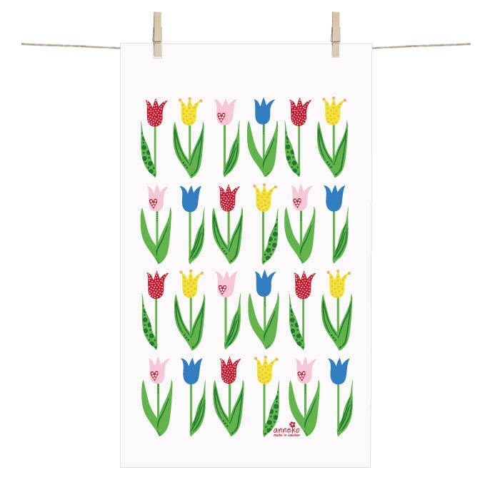 A Tulip Terry Cotton Hand Towel (12" x 20") with a grid of colorful stylized tulips, inspired by Anneko Design Sweden, is displayed hanging from two clothespins on a line.