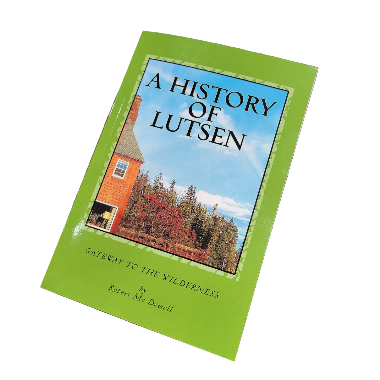 An autographed copy of A History of Lutsen by Robert McCain Dowell sits on a marble surface, featuring a green cover with a cabin and trees under a blue sky.