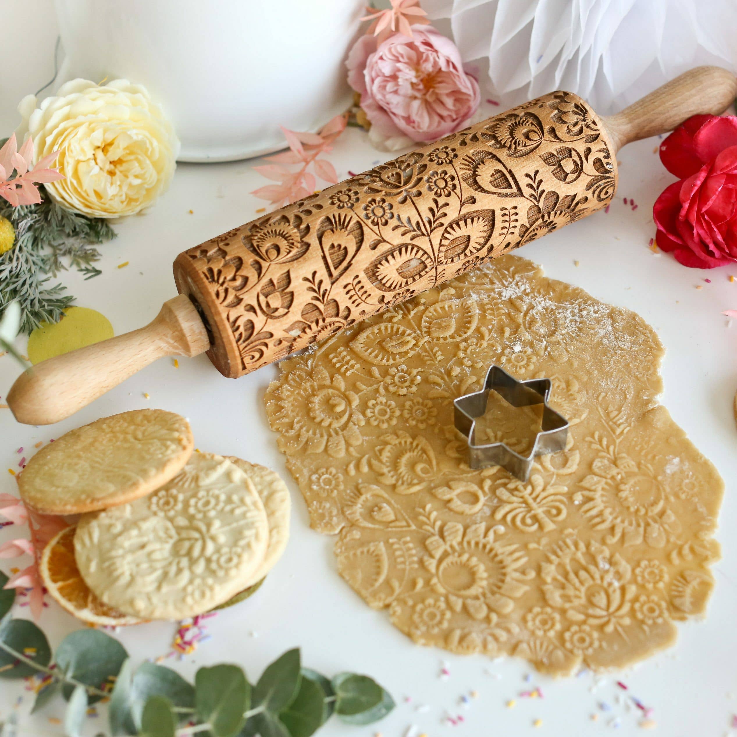 The Folk Pattern Embossing Rolling Pin Flowers comes with star-shaped cookie cutters and is surrounded by cookies and flowers, making it ideal for handmade gifts that enchant.