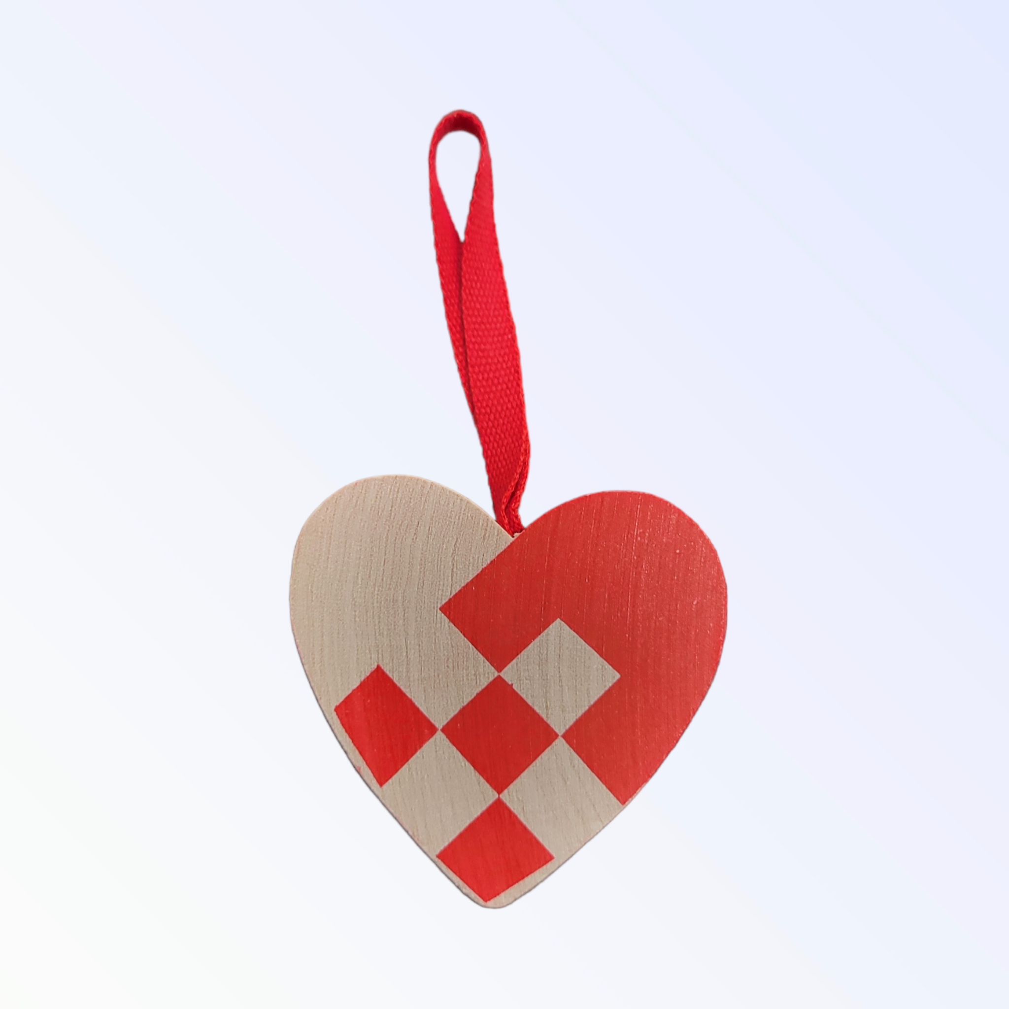 A delightful 2" Red Woven Heart Basket ornament, showcasing red and beige squares, hangs elegantly from a red ribbon against a light background, perfectly blending traditional design with natural beauty.