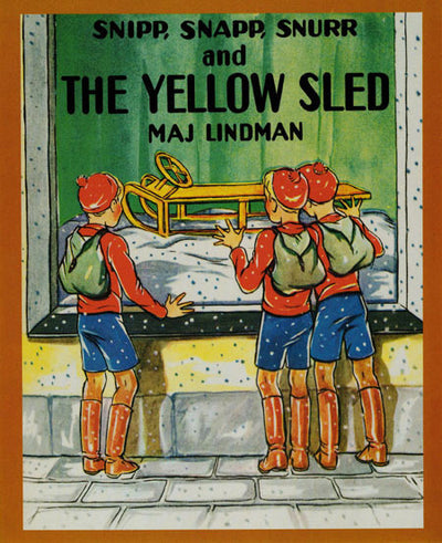 Three boys in matching red and blue winter outfits gaze at a yellow sled—Snipp, Snapp, and Snurr smile with excitement in the shop window. Snipp, Snapp, Snurr and the Yellow Sled by Maj Lindman is shown above them.