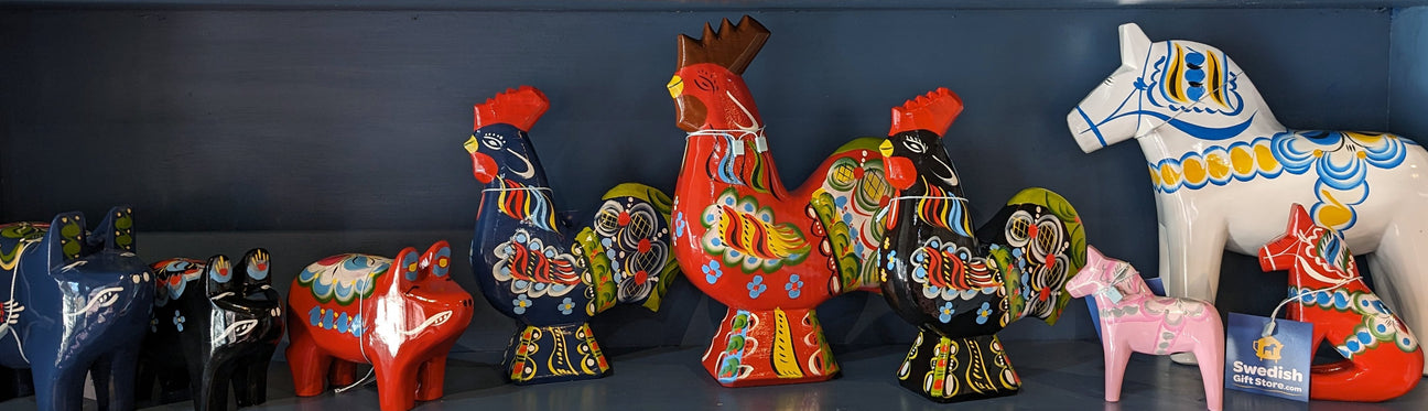 Colorful painted wooden figures of roosters, horses, and other animals displayed on a shelf.