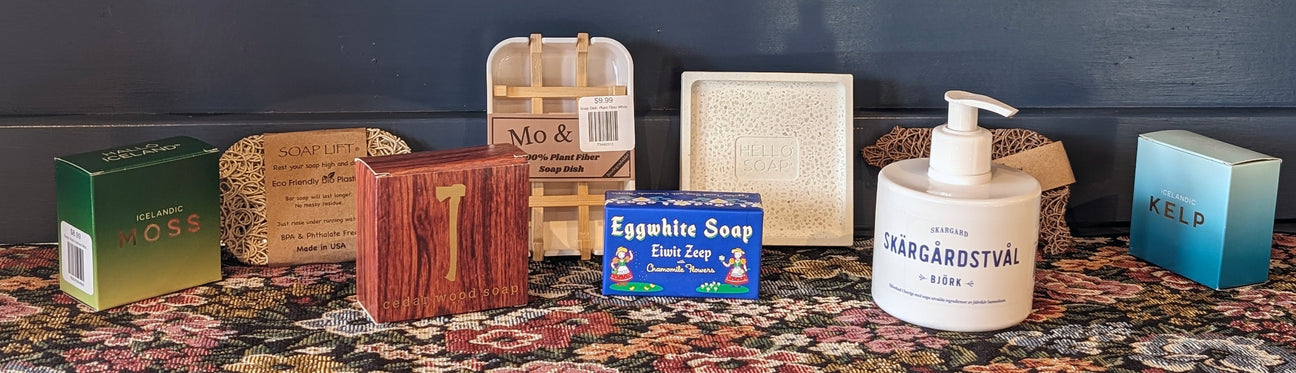 An assortment of various soap bars and a liquid soap bottle displayed on a decorative floral surface.