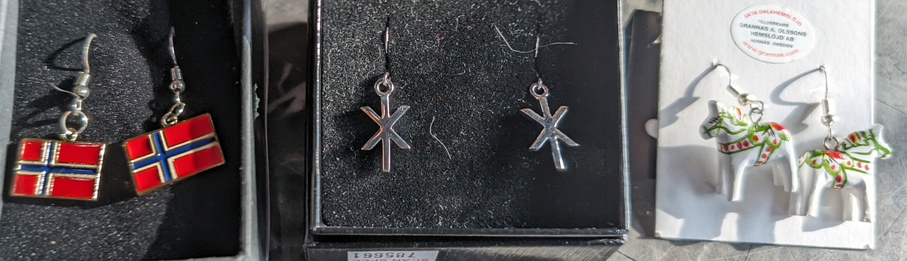 Three pairs of earrings: one with Norwegian flags, one with rune symbols, and one with white horse figures.