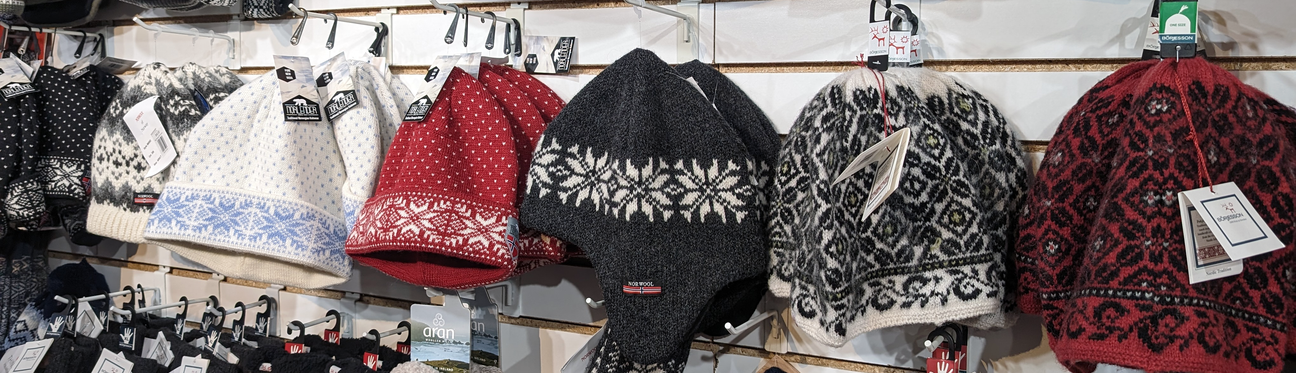 A display of woolen winter hats in various colors and patterns, hanging on a store wall.