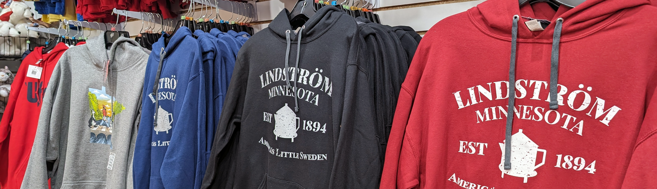 A rack of hoodies in various colors featuring Lindström Minnesota designs, displayed in a store.
