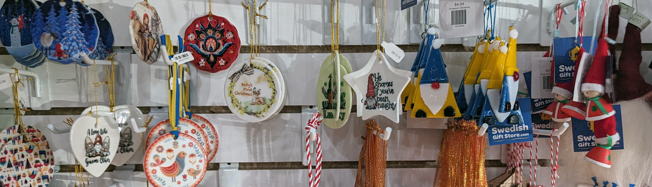 A display of various ceramic and wooden Christmas ornaments hanging on a slatted wall.