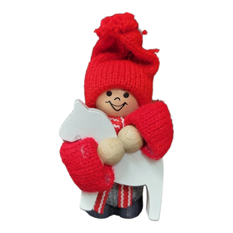 Wooden figurine with a smiling face, wearing a red knit hat and mittens, holding a white horse cutout.